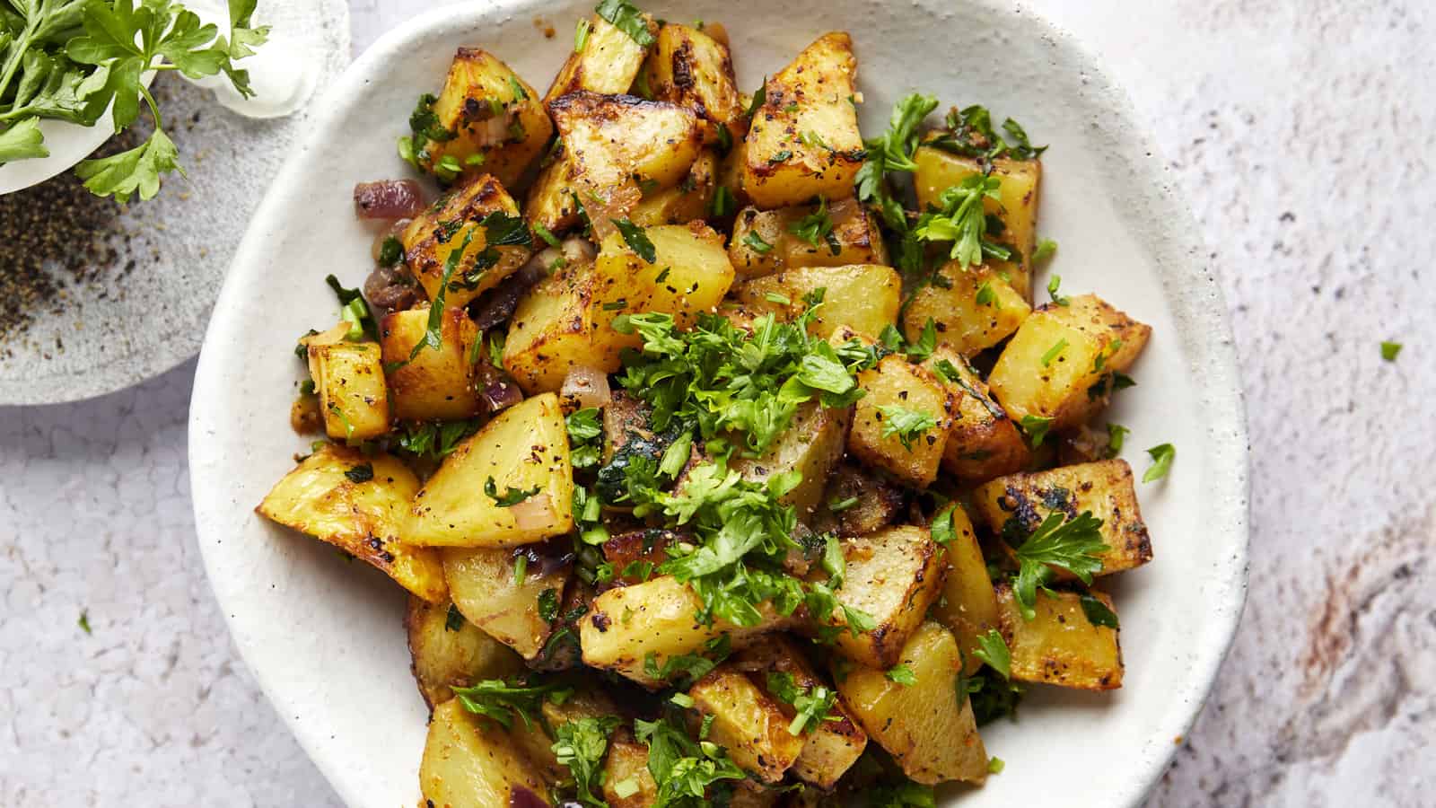 A plate of air fryer golden potatoes with harissa sauce topped with parsley.
