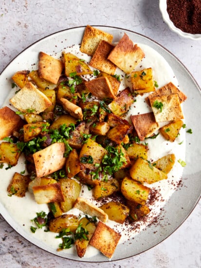 Harissa potatoes over whipped tahini sauce topped with fried pita.