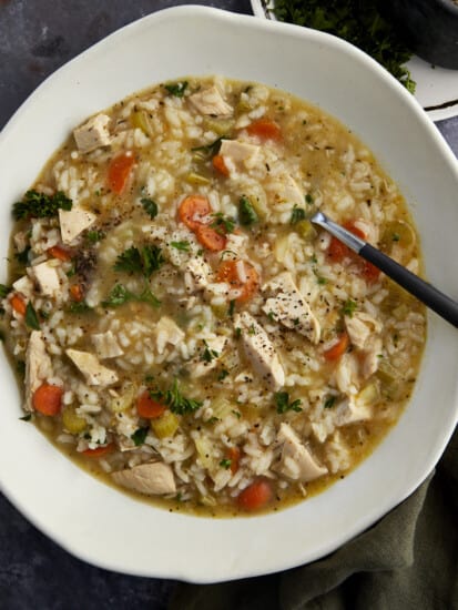 A bowl of creamy chicken and rice soup with a spoon sticking out.