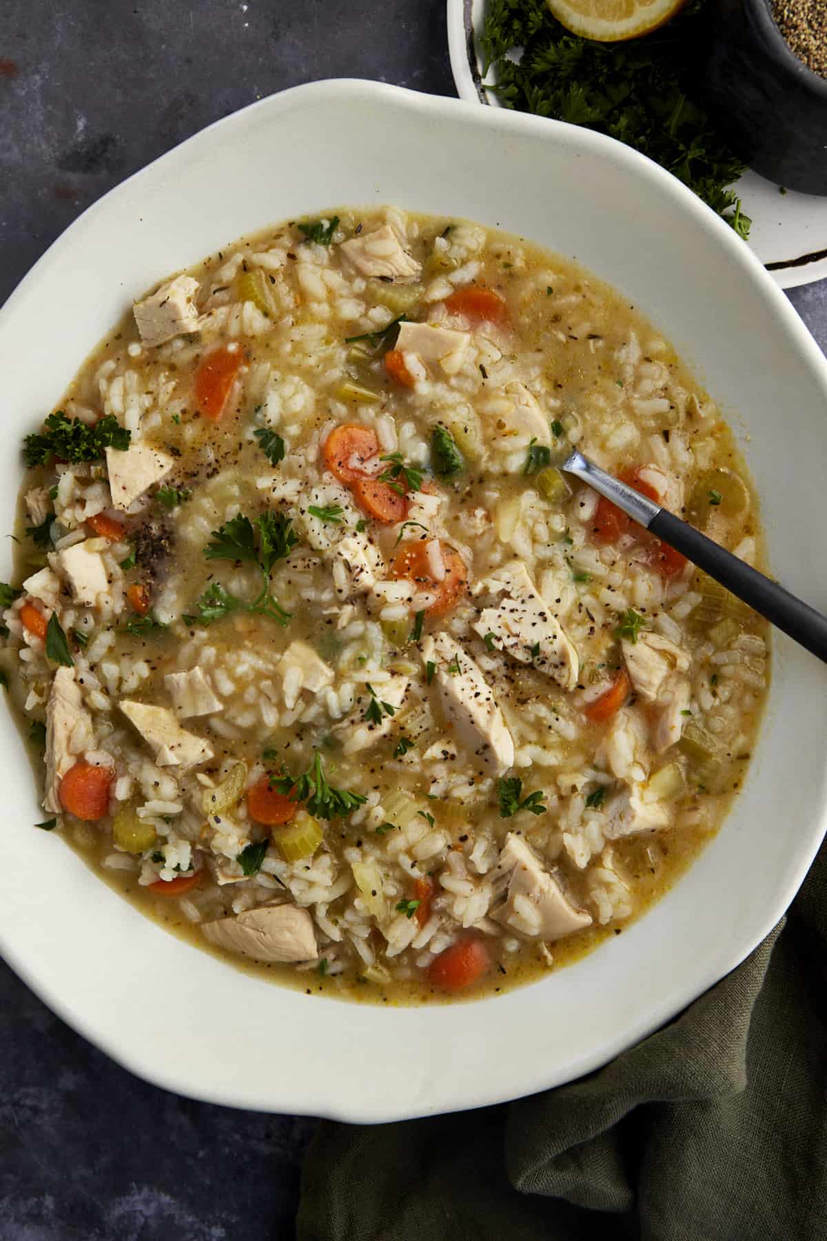 Overhead image of a bowl of chicken and rice soup with a spoon dipped in. 