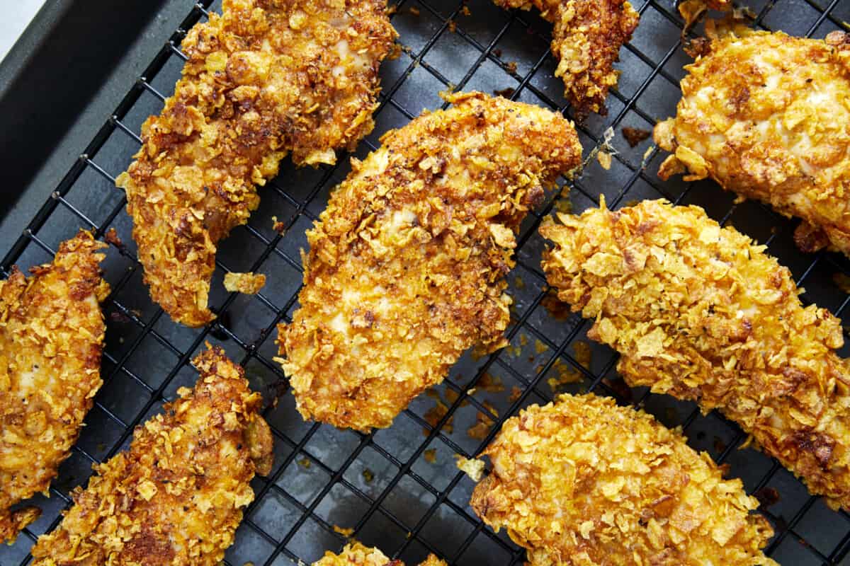 Baked cornflake chicken tenders on a wire rack.
