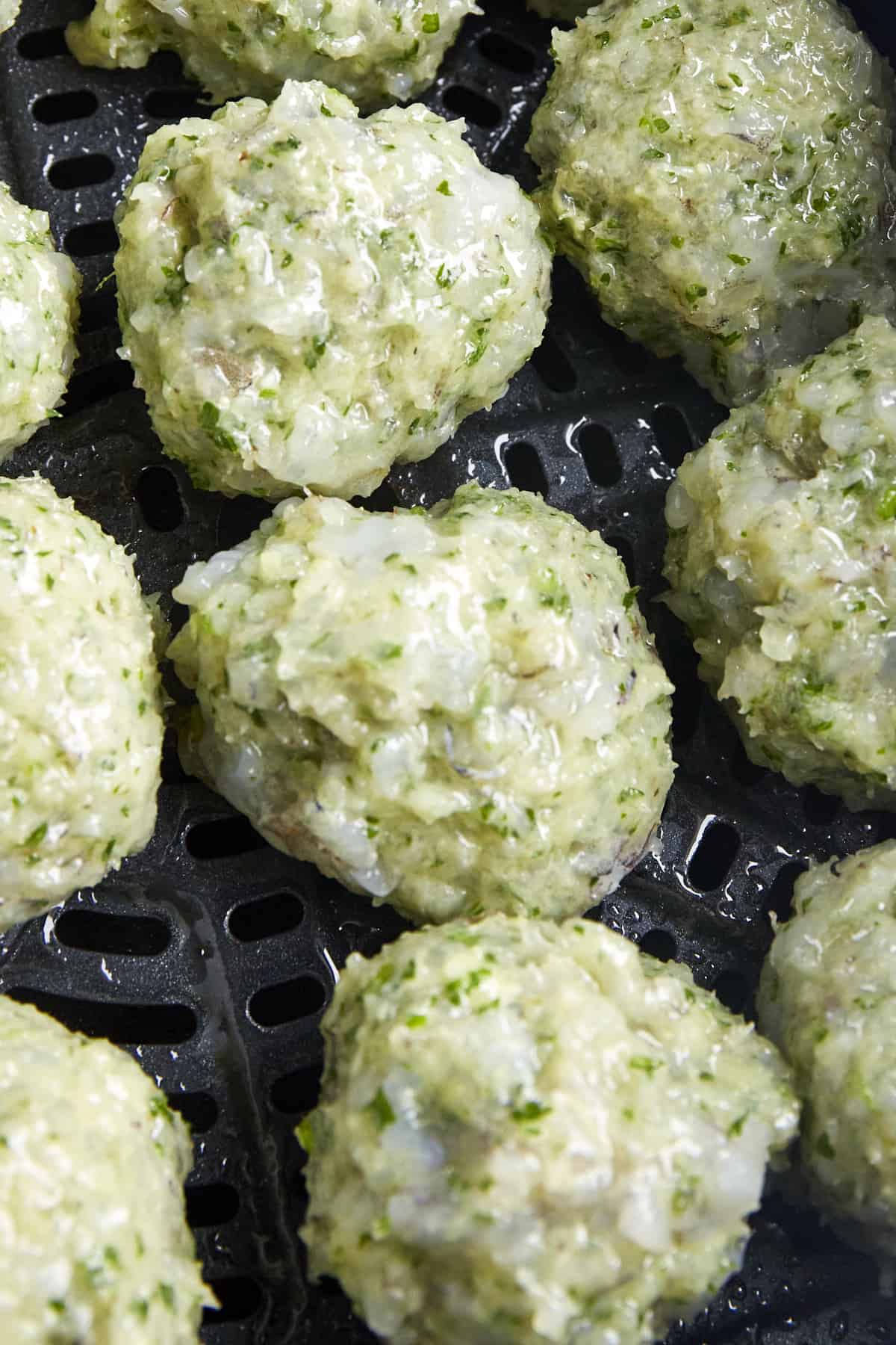 Raw shrimp kofta meatballs in an air fryer basket.