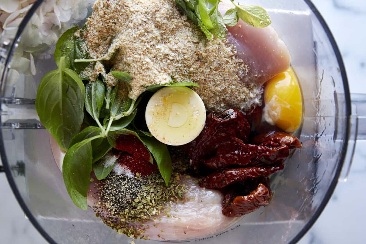 Ingredients for sun-dried tomato chicken meatballs in a food processor.