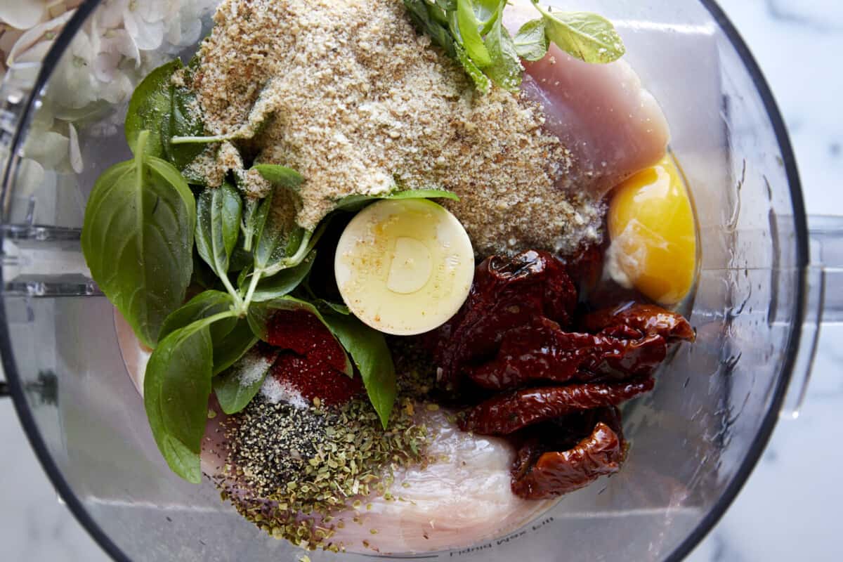 Ingredients for sun-dried tomato chicken meatballs in a food processor. 