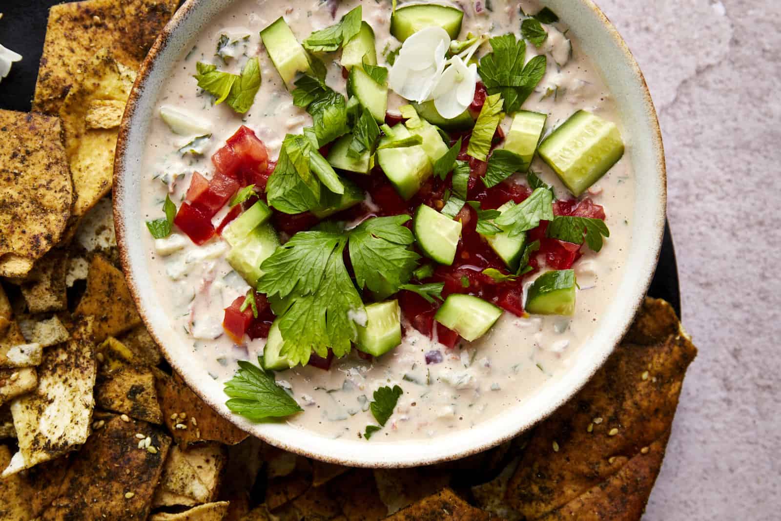 Overhead image of a bowl of tahini salad with pita chips.