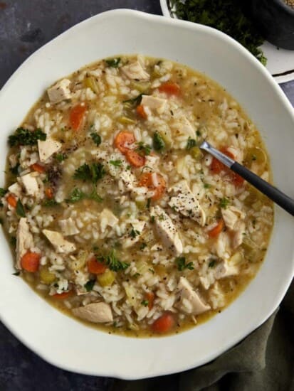A bowl of creamy chicken and rice soup with a spoon sticking out.