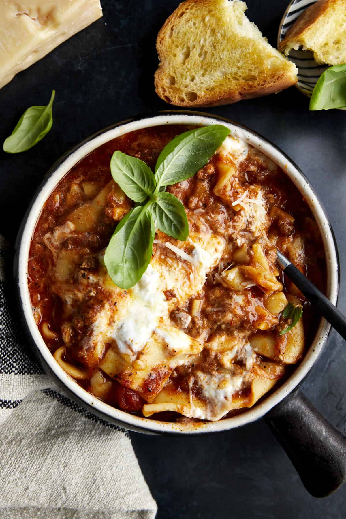 A bowl of lasagna soup with toasted bread on the side. 