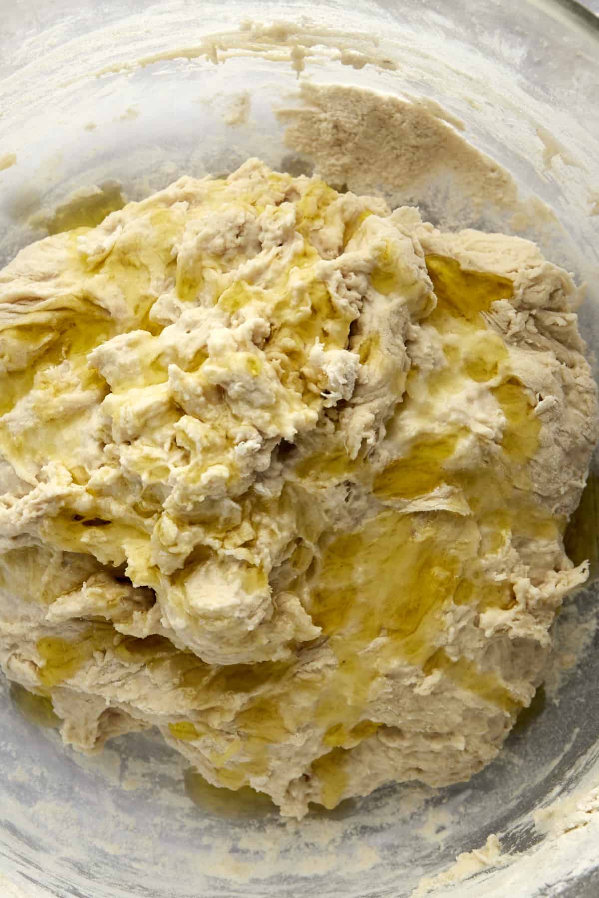 Oil drizzled over bread dough in a bowl.