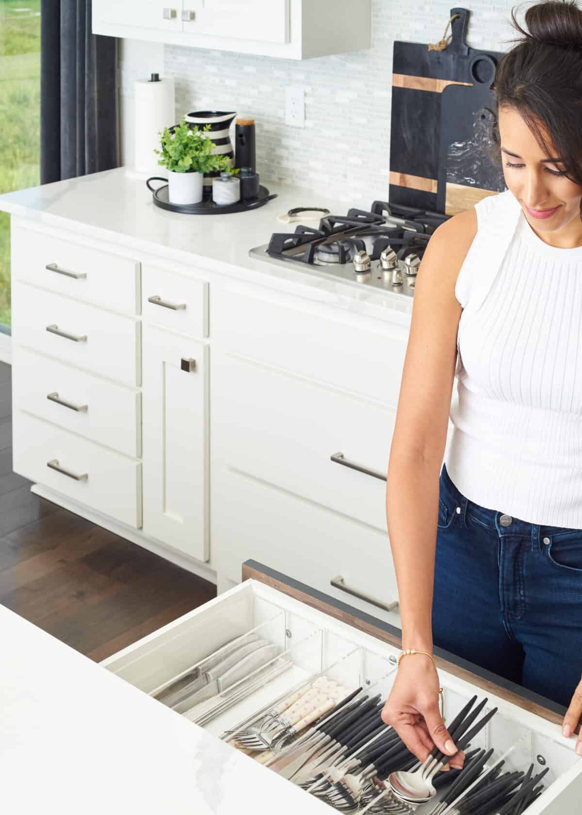 woman placing spoons in kitchen drawer.