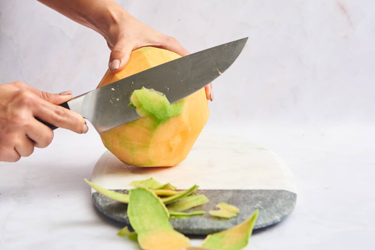 Rind of a cantaloupe being trimmed off. 