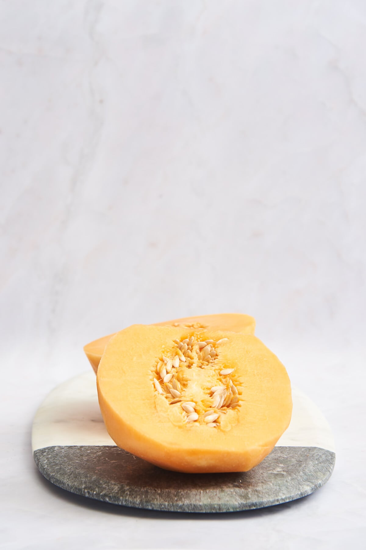 Peeled cantaloupe halves on a cutting board. 