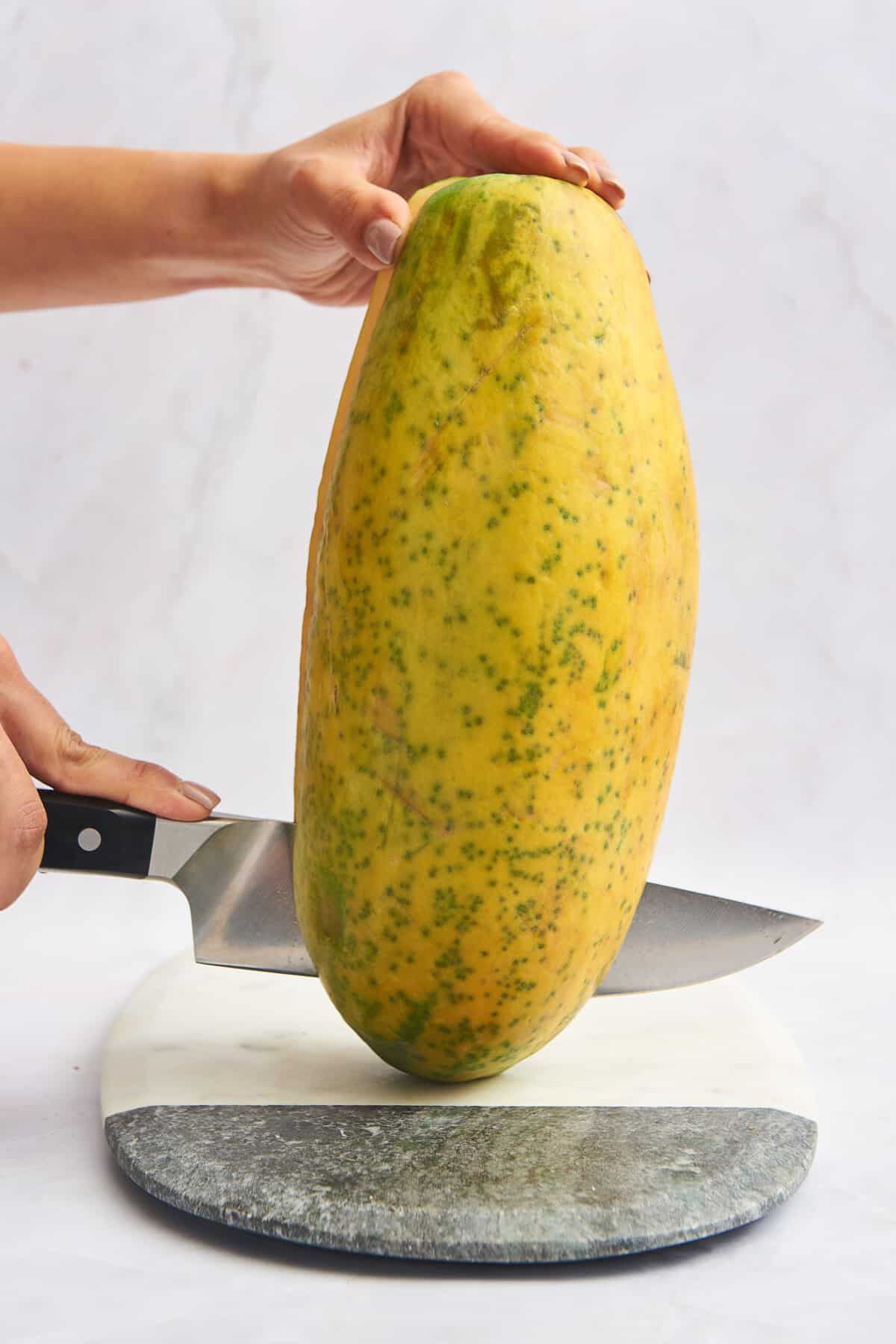 A knife slicing a papaya in half. 