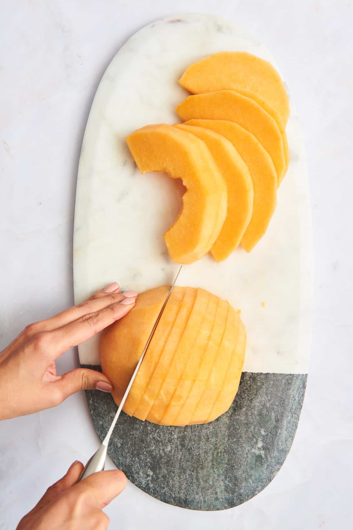 A cantaloupe being sliced into strips. 