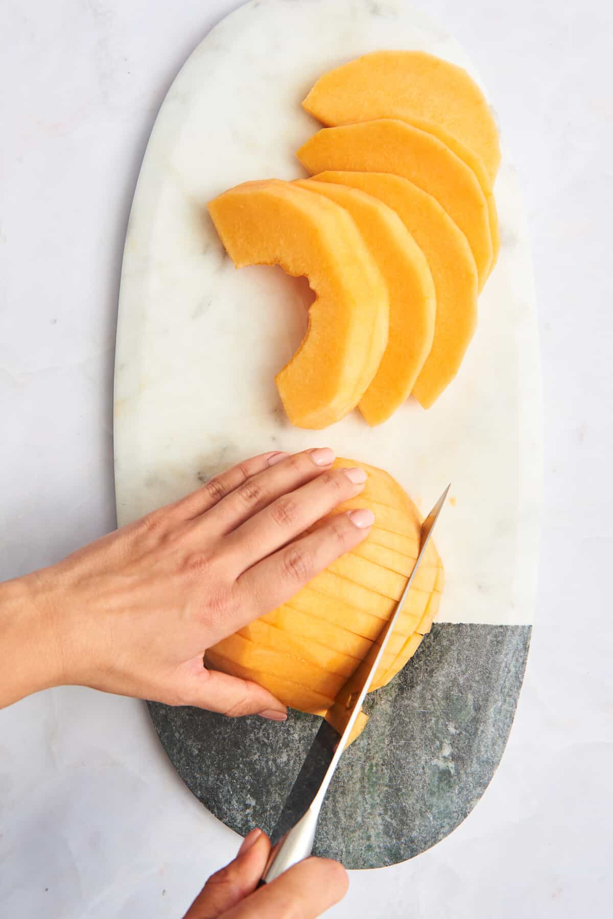 A cantaloupe being sliced into cubes. 