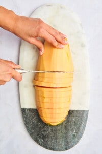 A papaya being cut into long strips.
