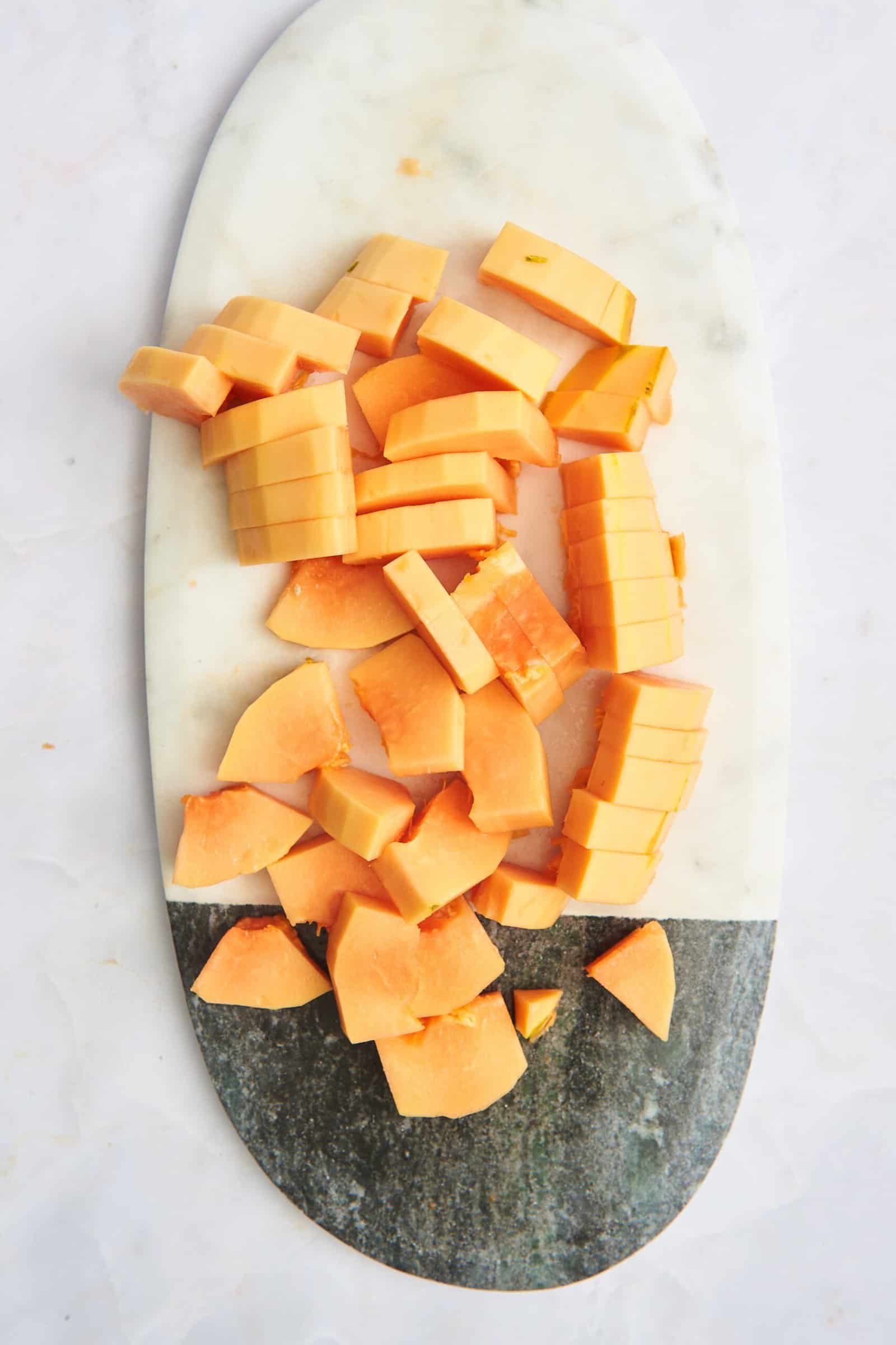 Pieces of papaya on a cutting board.