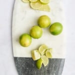 Lime rounds, whole limes, and lime wedges on a cutting board.