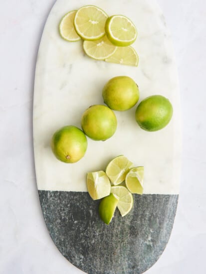 Lime rounds, whole limes, and lime wedges on a cutting board.