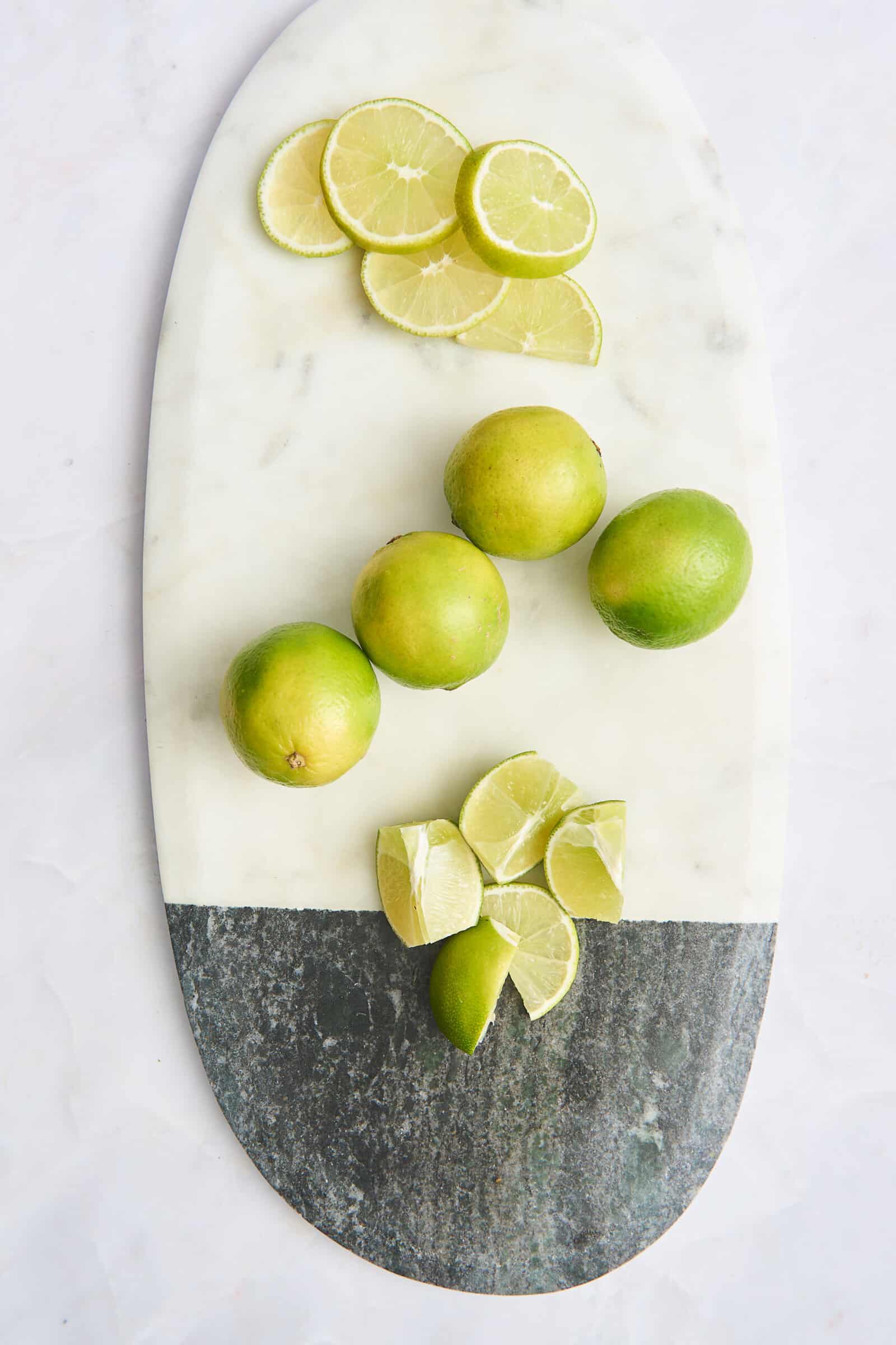 Lime rounds, whole limes, and lime wedges on a cutting board.