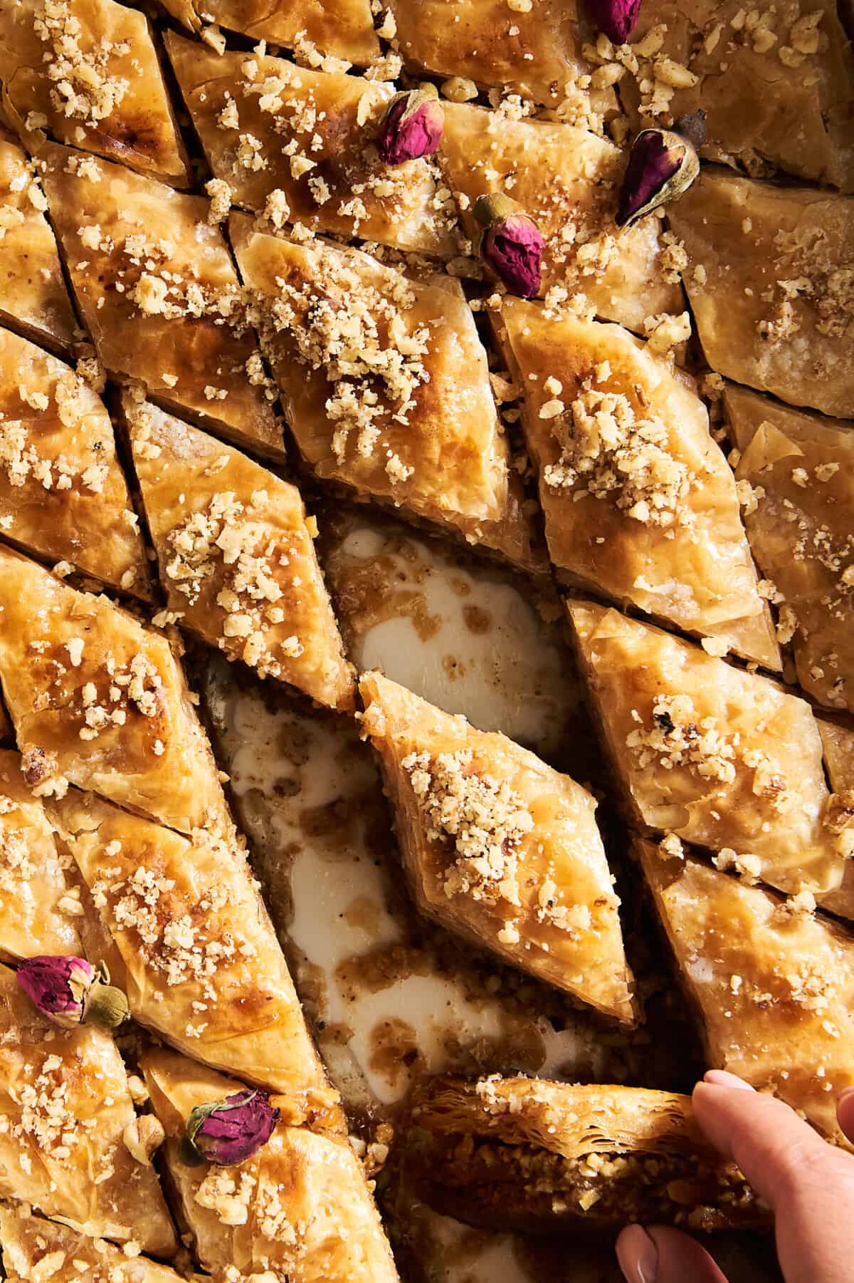 A baking dish of baklava pieces with a few pieces missing. 