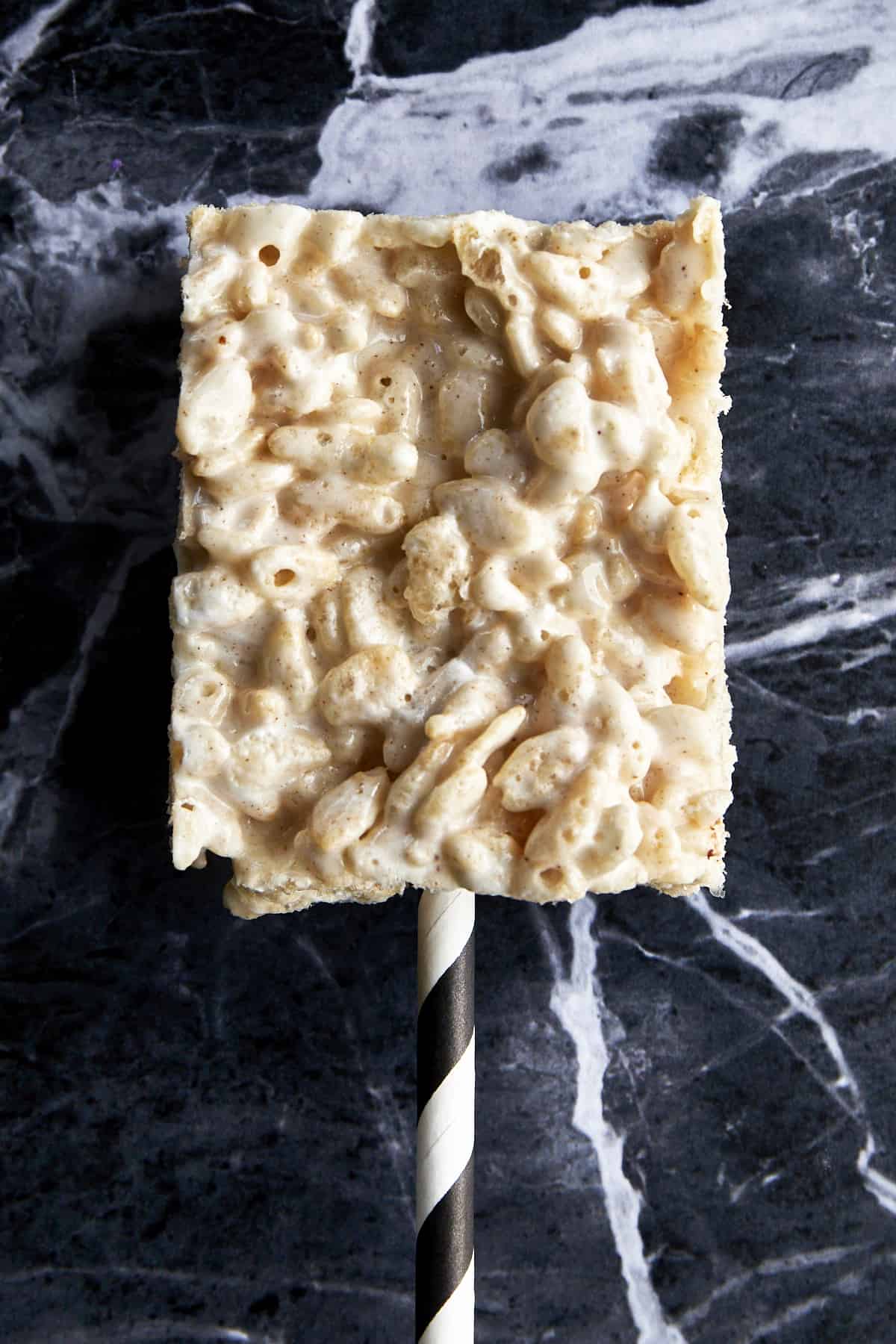 A plain rice krispie treat with a straw sticking out. 