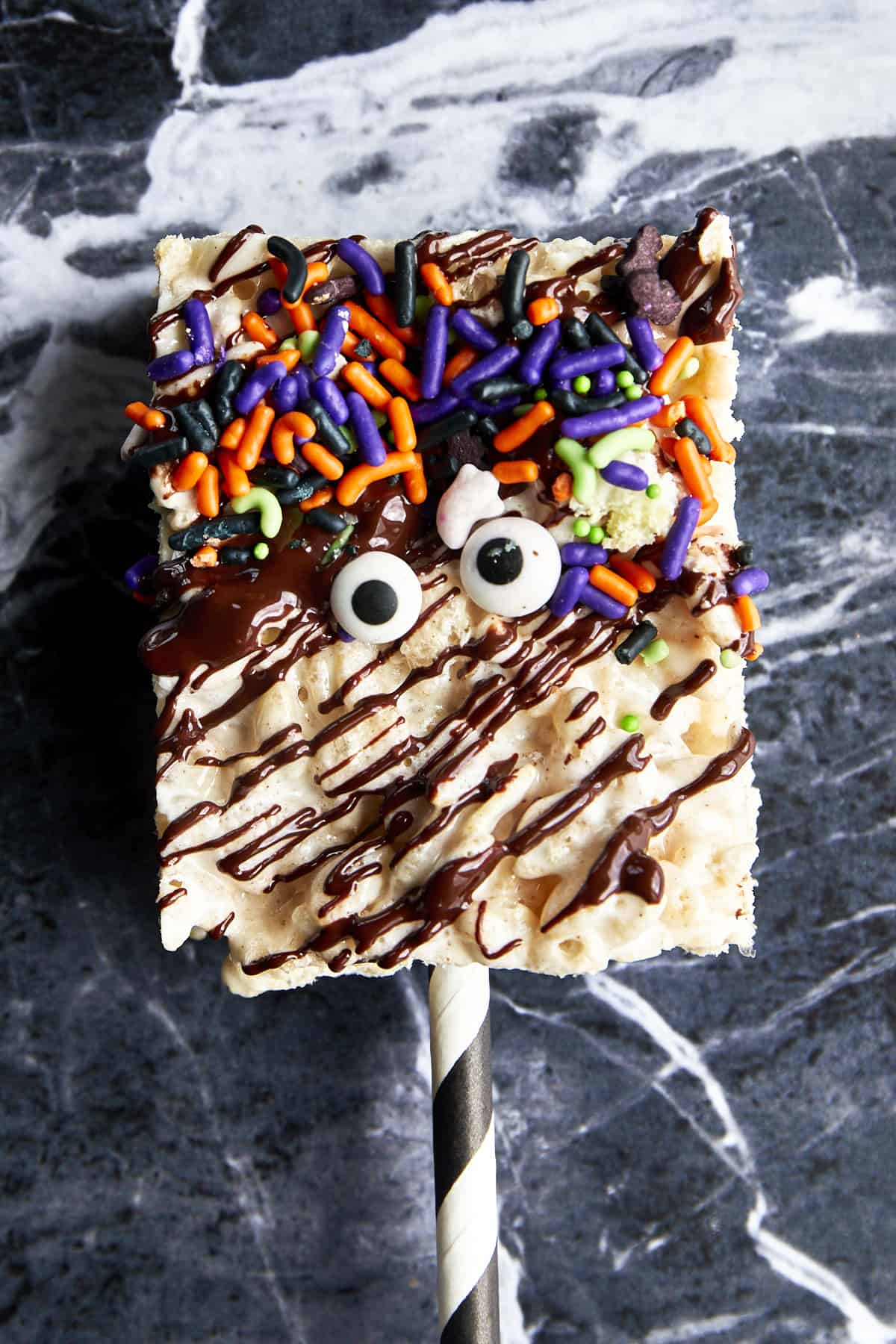 A Halloween rice krispie treat topped with chocolate drizzle, sprinkles, and candy eyes. 