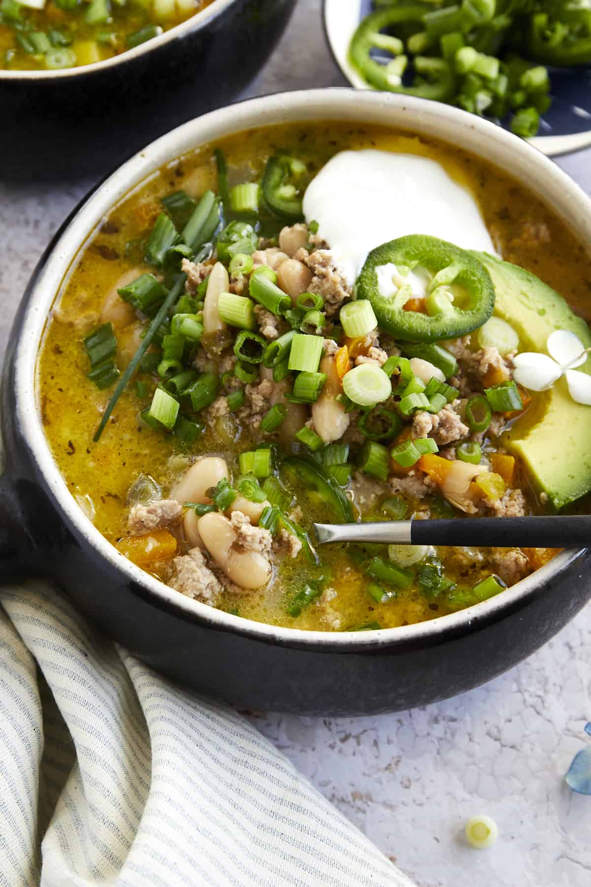 A bowl of healthy white turkey chili with a spoon sticking out. 