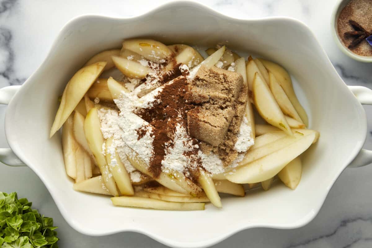 Pears in a baking dish topped with flour, brown sugar, and cinnamon. 