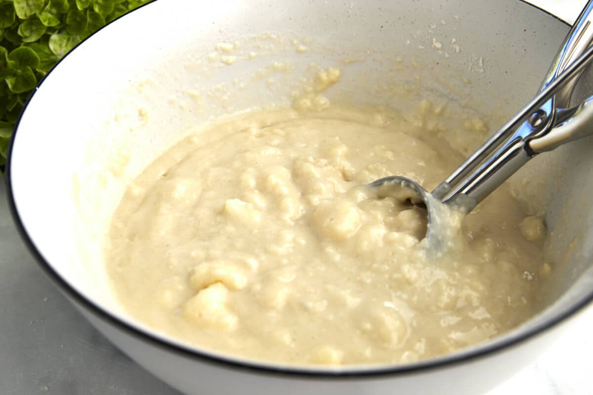 Biscuit filling in a bowl with a cookie scoop for a pear cobbler. 