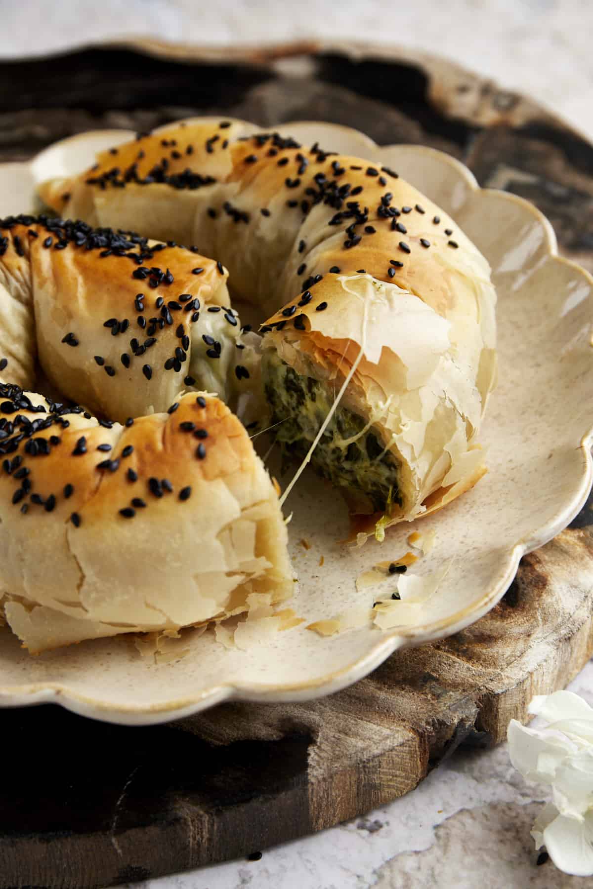Side view of a sliced phyllo spanakopita roll exposing the cheese and spinach filling. 