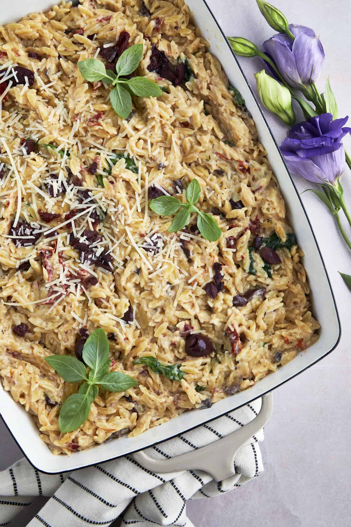 A baking dish full of spinach and sun-dried tomato boursin orzo bake. 