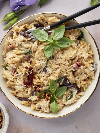 A bowl of spinach and sun-dried tomato boursin orzo bake.