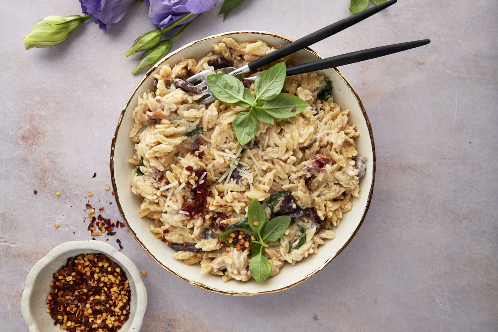 A bowl of spinach and sun-dried tomato boursin orzo bake.
