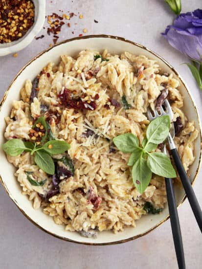 A bowl of spinach and sun-dried tomato boursin orzo bake.