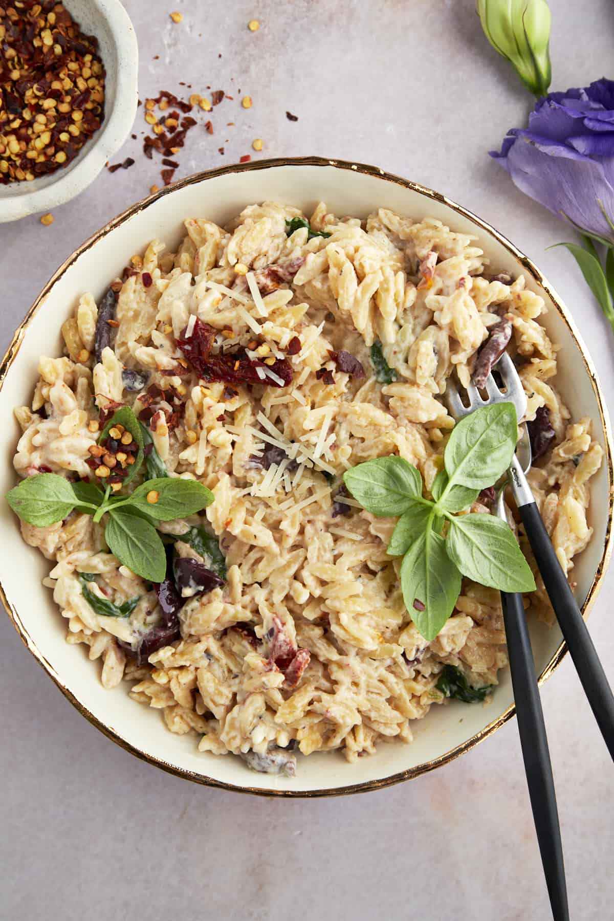 A bowl of spinach and sun-dried tomato boursin orzo bake. 