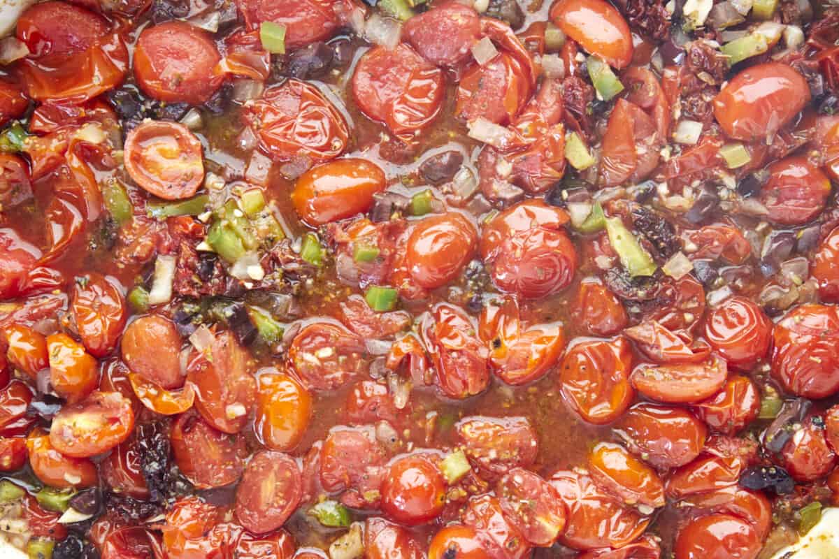 Baked tomatoes, olives, and bell peppers in a dish. 