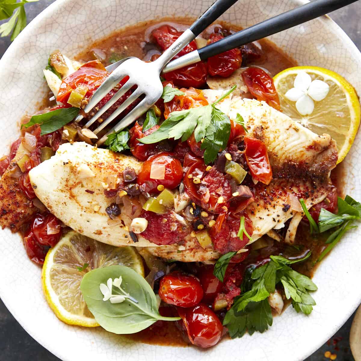A bowl of Mediterranean tilapia with two forks.