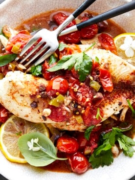 A bowl of Mediterranean tilapia with two forks.