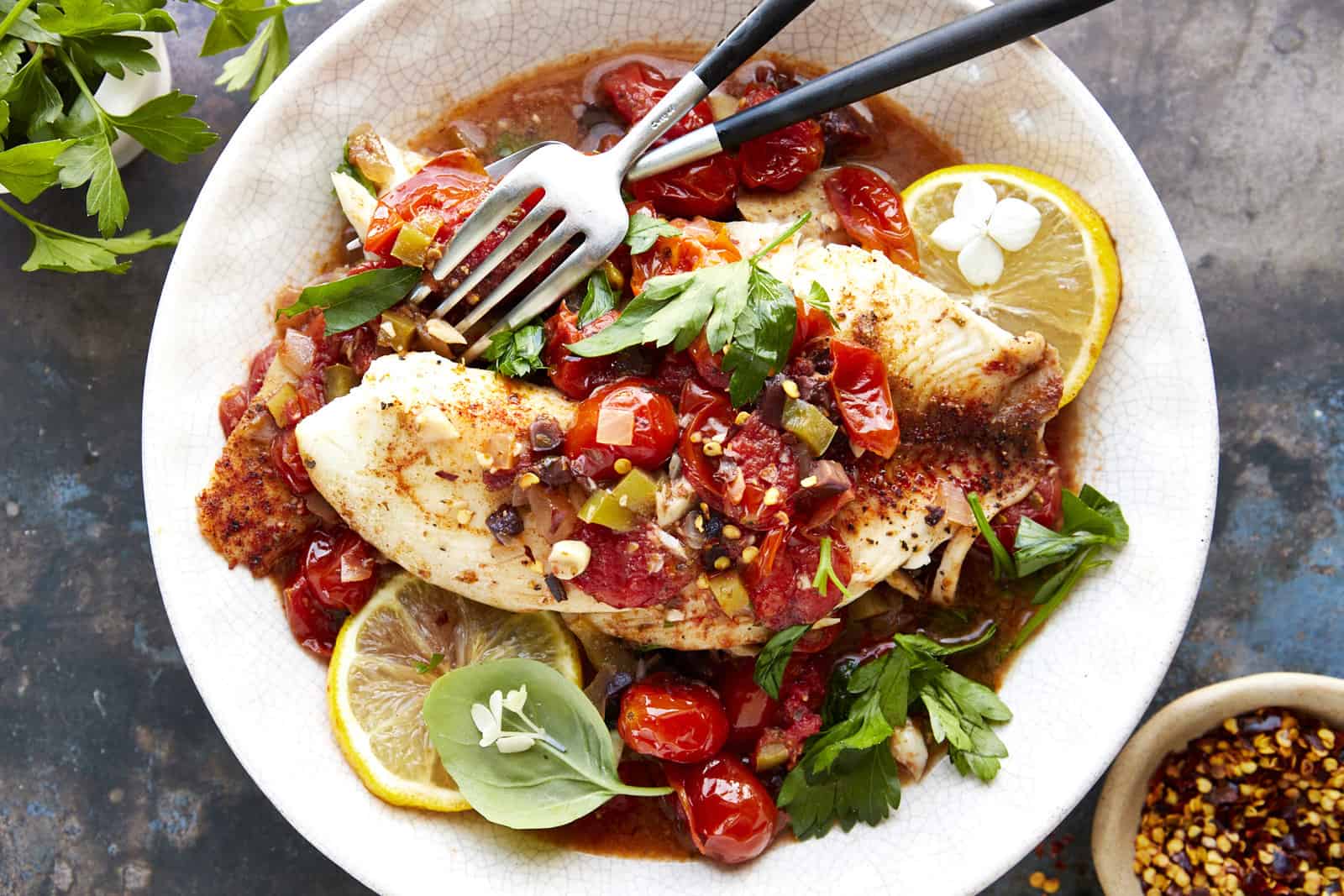 A bowl of Mediterranean tilapia with two forks.
