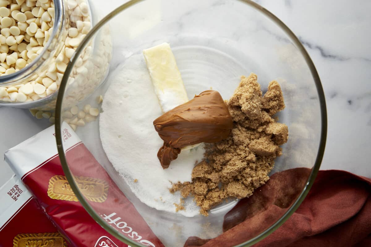 Butter, white sugar, brown sugar, and Biscoff cookie butter in a bowl. 