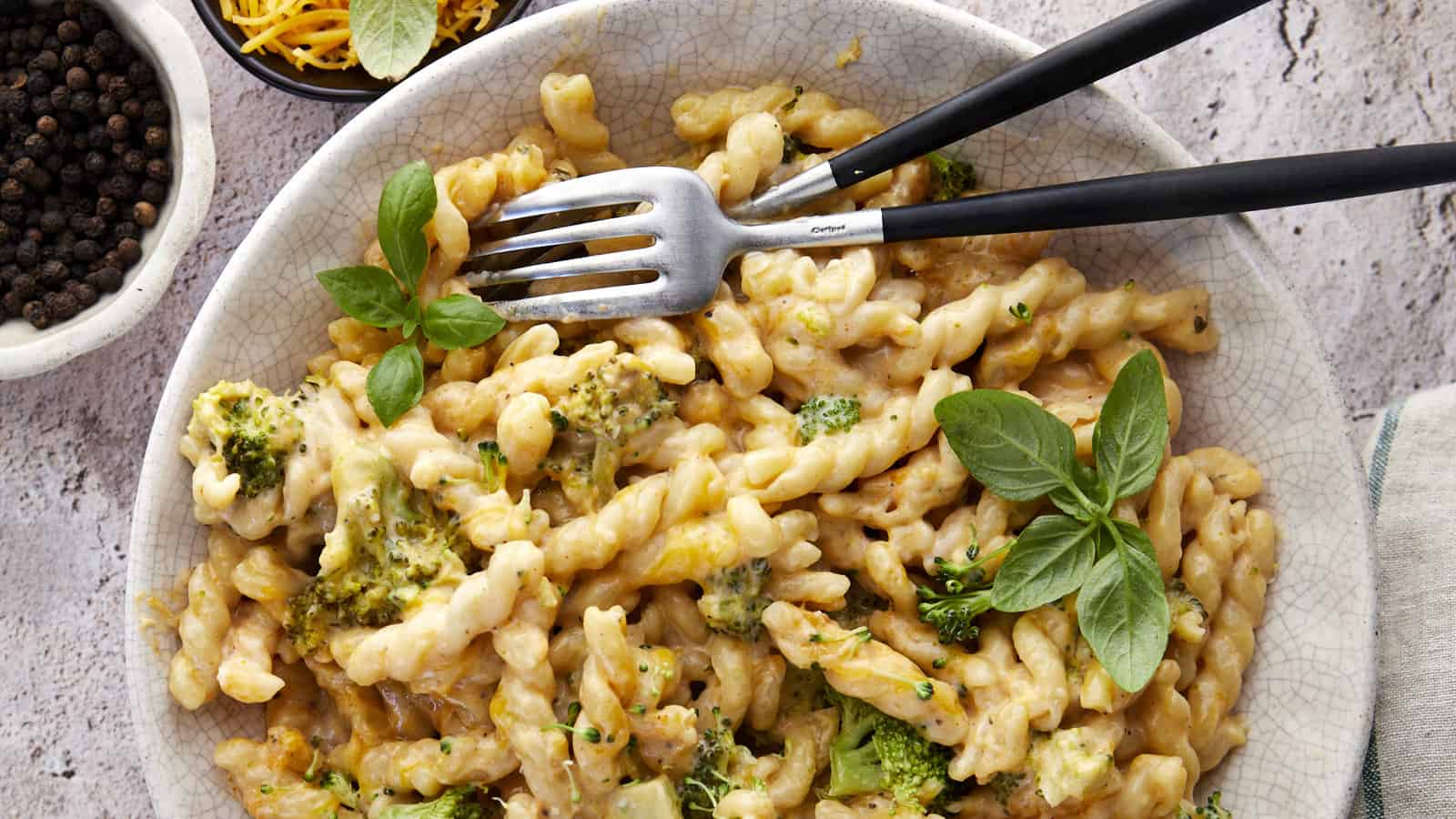 Overhead image of a bowl of baked broccoli mac and cheese with two forks.