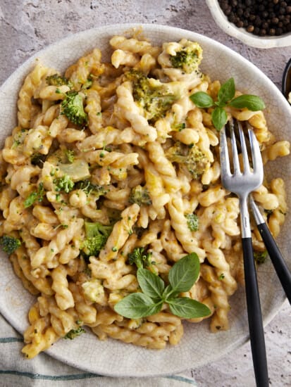 A bowl of baked broccoli mac and cheese with two forks on the side.