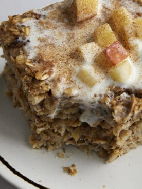 A serving of baked apple oatmeal topped with milk and apples.