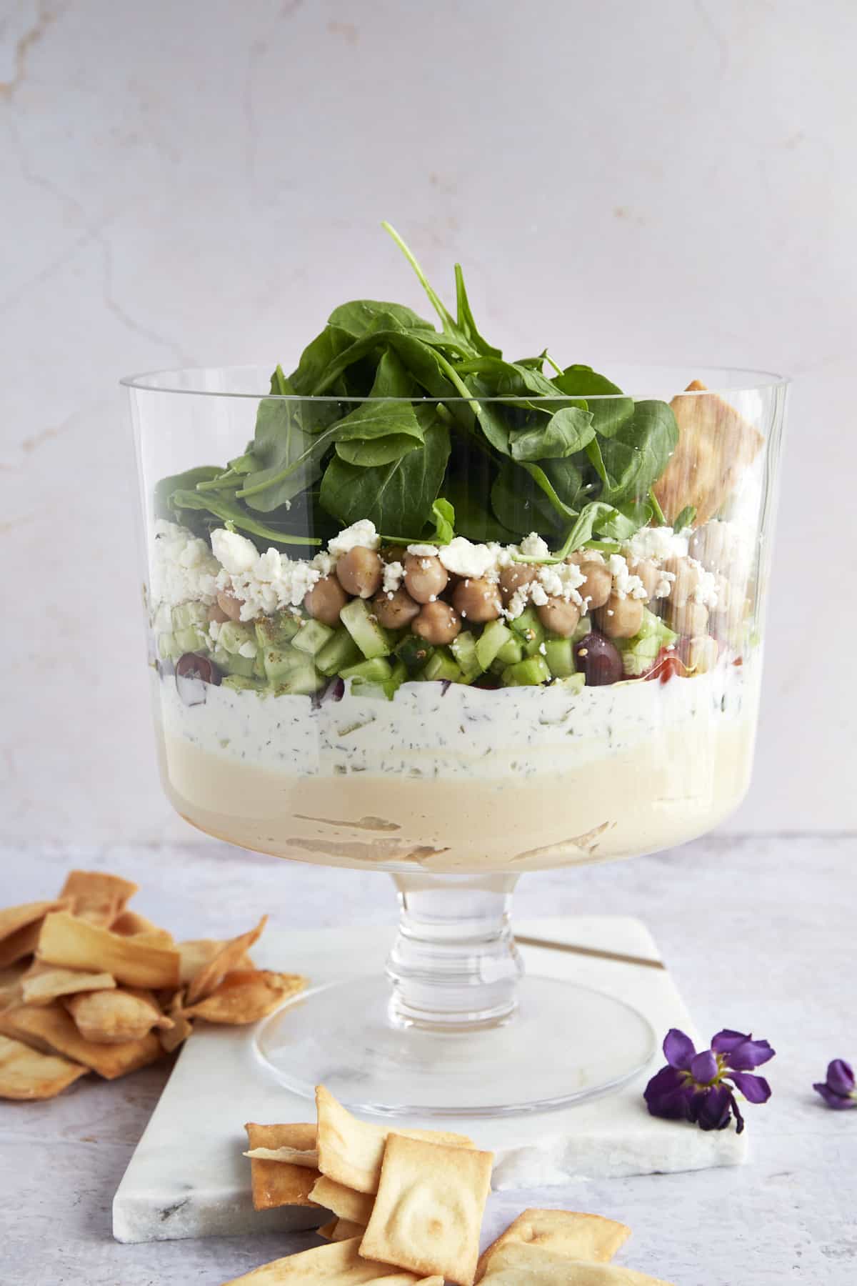 A trifle bowl full of 7 layer Greek dip. 