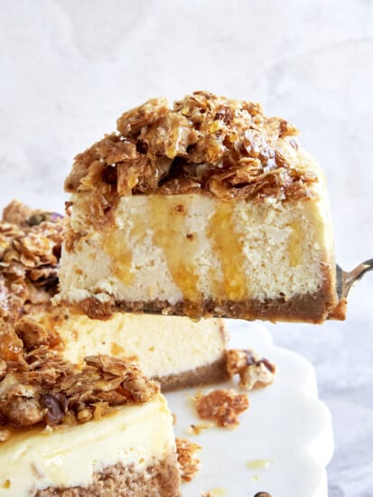 A slice of baklava cheesecake being lifted from a cake stand.