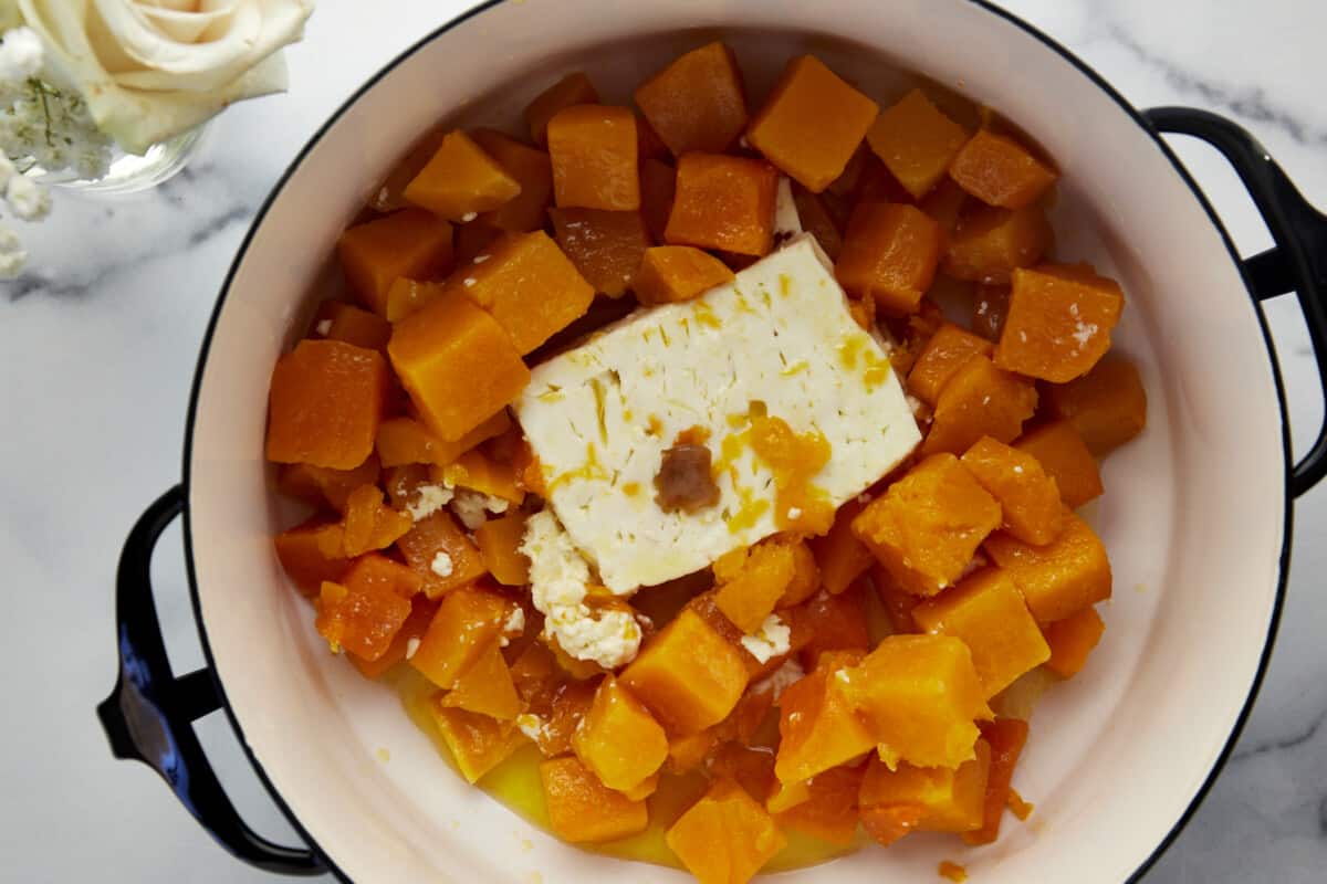 Cooked butternut squash, feta, nad garlic in a pot. 