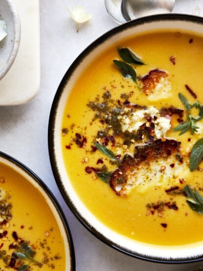 Two bowls of roasted butternut squash topped with feta crisps.