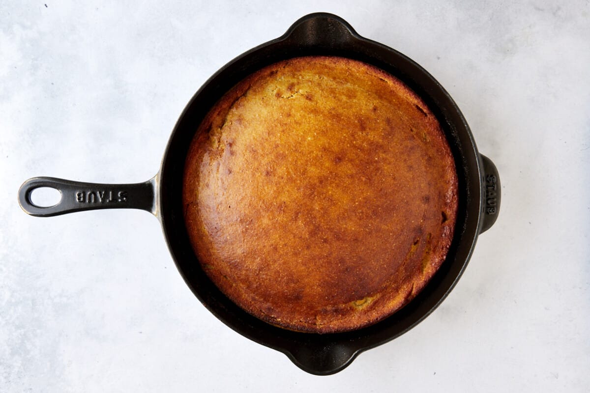 A cast iron skillet full of baked brown butter cornbread. 