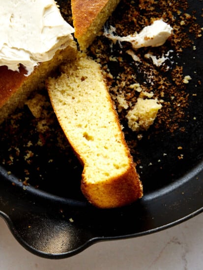 A piece of brown butter cornbread on its side in a skillet.