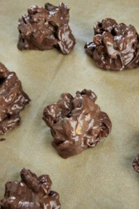 Hot chocolate caramel pecan clusters on a parchment paper lined baking sheet.